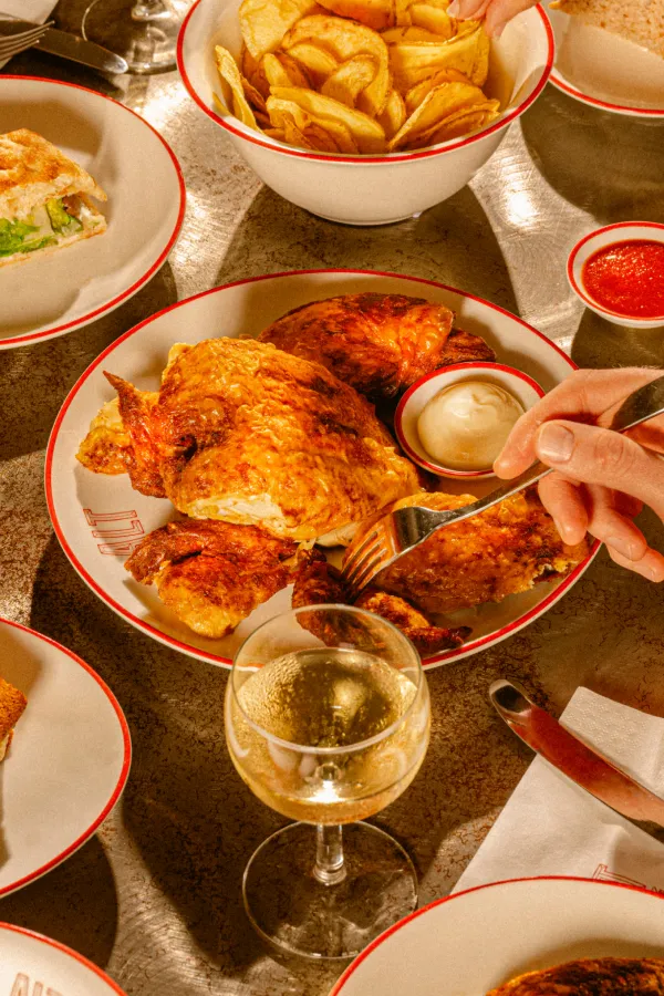 Table set with fried chicken, potato chips, mayonnaise and ketchup, focaccia and glass of white wine